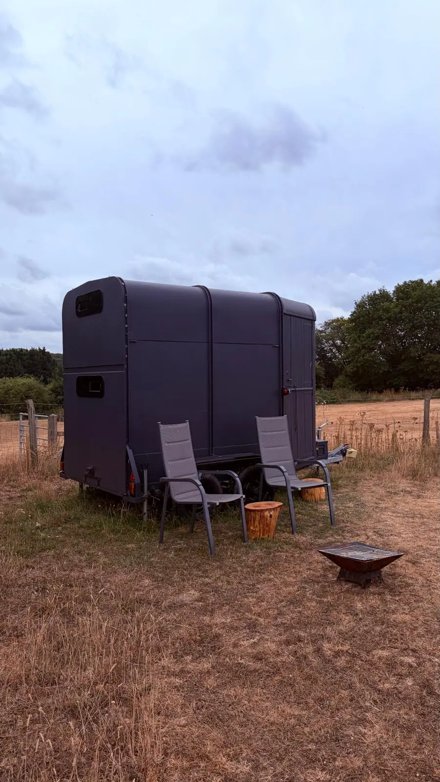 Converted horse box with two chairs and a fire pit on the grass
