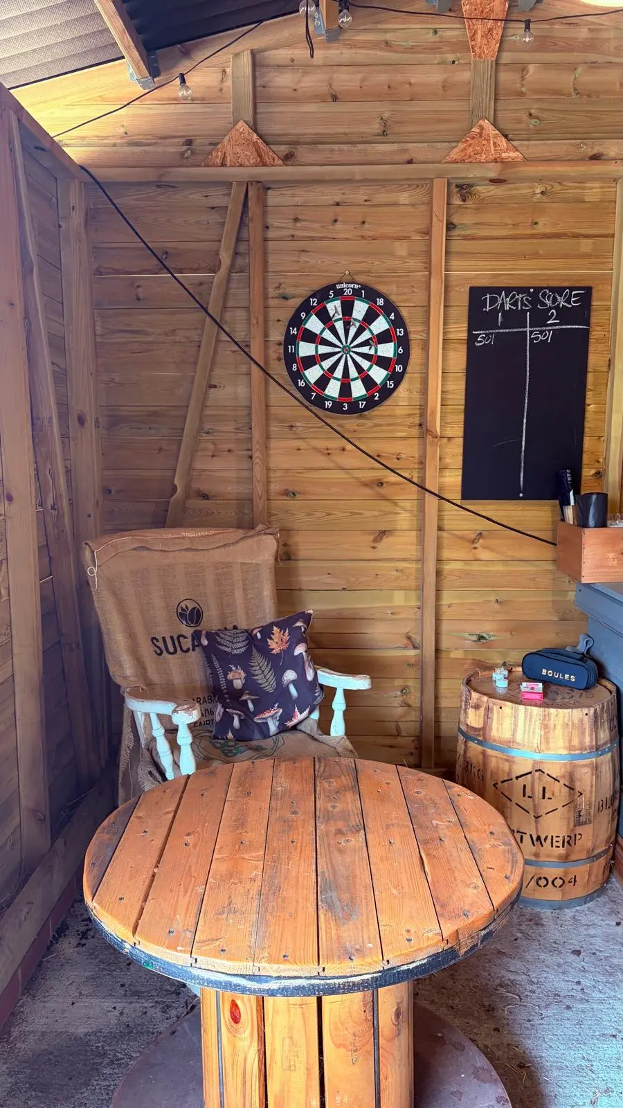 Darts corner in the barn with an armchair and wooden table